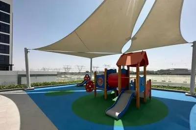 a playground with an umbrella and a slide at Vacay Lettings Charming Retreat Azizi Riviera in Dubai