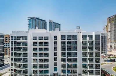 a white apartment building with tall buildings in the background at Vacay Lettings Charming Retreat Azizi Riviera in Dubai