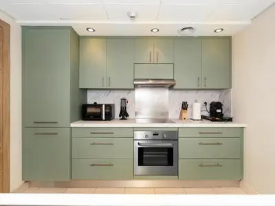 a kitchen with green cabinets and a stove at Royal Vista - Luxury 2BR Apartment at Burj Views Tower A - Downtown in Dubai