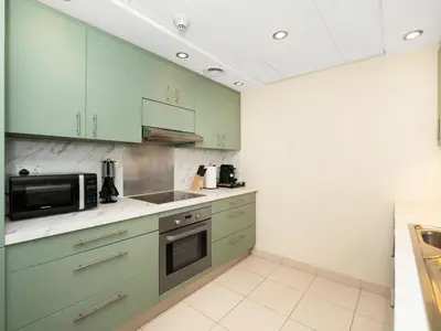 a kitchen with green cabinets and a microwave at Royal Vista - Luxury 2BR Apartment at Burj Views Tower A - Downtown in Dubai