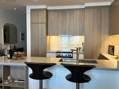 a kitchen with a sink and two bar stools at Dubai Marina stunning views holiday apartment Stella Maris Tower in Dubai