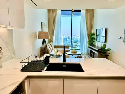 a kitchen with a sink and a living room at Modern 1br In Jvc Pool, Balcony & Free Parking in Dubai