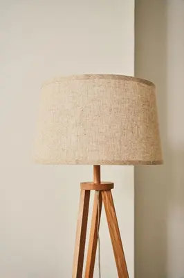 a lamp with a tan lampshade on a wooden tripod at Luxury Seaview 2BR - Paramount Midtown - 6 Guests - 64F Pool Access & Burj View in Dubai