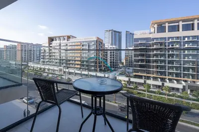 a table and chairs on a balcony with a view of a city at Chic Studio in Azizi Riviera 46, Al Merkadh by Deluxe Holiday Homes in Dubai