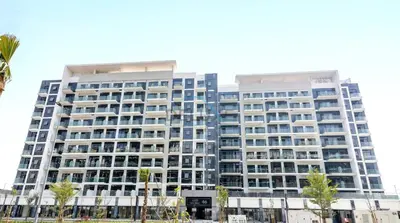 a tall building with palm trees in front of it at Chic Studio in Azizi Riviera 46, Al Merkadh by Deluxe Holiday Homes in Dubai