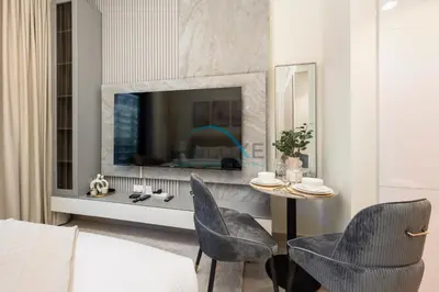 a living room with a table and two chairs and a television at Chic Studio in Azizi Riviera 46, Al Merkadh by Deluxe Holiday Homes in Dubai