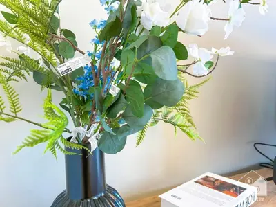 a blue vase with flowers in it on a table at Elegant Stay in Meydan Balcony & Stunning Views in Dubai