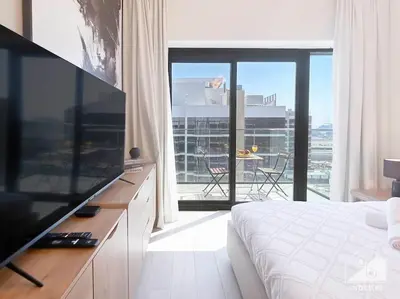 a bedroom with a television and a balcony with a table at Elegant Stay in Meydan Balcony & Stunning Views in Dubai