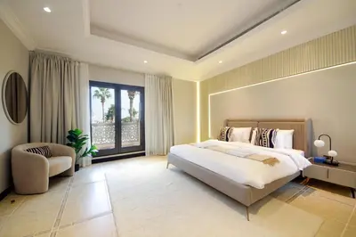 a bedroom with a bed and a chair and a window at Cozy 4BR Maid Villa at Canal Cove Palm Jumeirah in Dubai