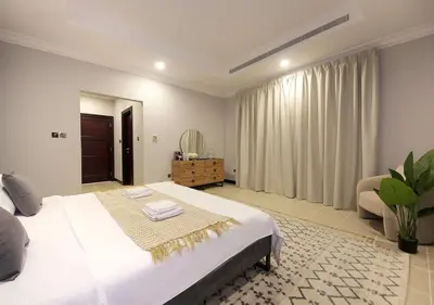 a bedroom with a large white bed and a chair at Cozy 4BR Maid Villa at Canal Cove Palm Jumeirah in Dubai