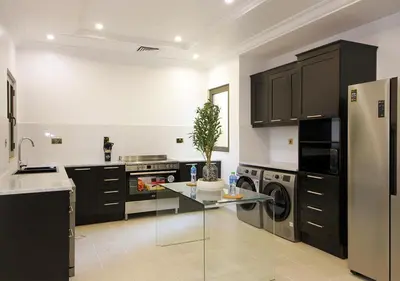 a kitchen with black cabinets and a glass table at Cozy 4BR Maid Villa at Canal Cove Palm Jumeirah in Dubai
