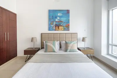 a white bedroom with a large bed with two lamps at Frank Porter - Burj Views West in Dubai