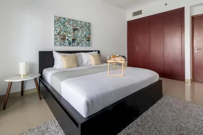 a bedroom with a large bed with a table on it at Frank Porter - Time Place Tower in Dubai