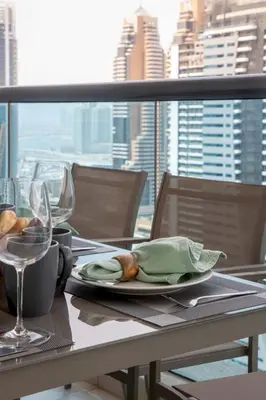 a table with a plate of food and wine glasses at Frank Porter - Time Place Tower in Dubai