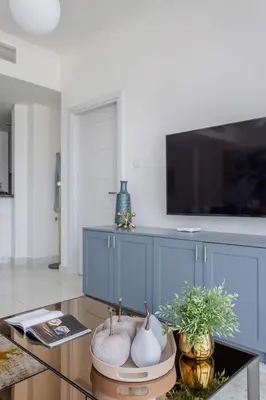 a living room with a glass table and a tv at Frank Porter - Damac Heights in Dubai