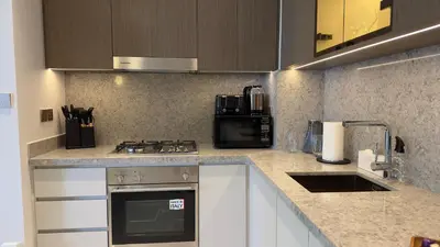 a kitchen with a stove and a microwave at Guest Favorite 1BR Designer Apt with Beach Access by Vibel in Dubai