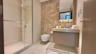 a bathroom with a shower and a toilet and a sink at Guest Favorite 1BR Designer Apt with Beach Access by Vibel in Dubai