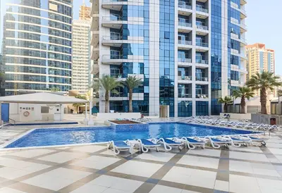 a swimming pool with lounge chairs and buildings at Stunning 1 bedroom in JBR with Balcony - Dubai Marina Mall view in Dubai