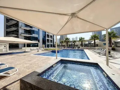a swimming pool with an umbrella on a building at Stunning 1 bedroom in JBR with Balcony - Dubai Marina Mall view in Dubai