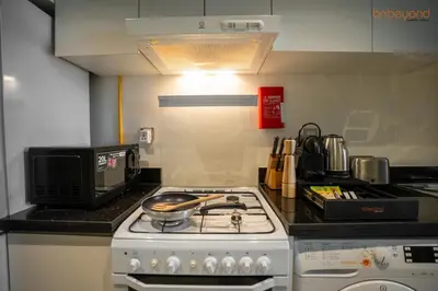 a kitchen with a stove and a microwave at Quirky Studio Apartment in Damac Ghalia in Dubai