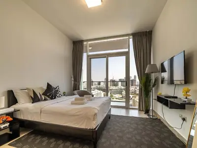 a bedroom with a large bed and a large window at Brand New Premium Studio In JVC in Dubai