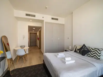 a bedroom with a large bed and a table at Brand New Premium Studio In JVC in Dubai