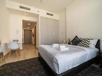 a bedroom with a large bed with white sheets at Brand New Premium Studio In JVC in Dubai
