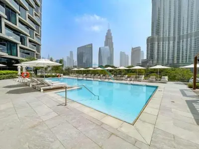 a large swimming pool with chairs and umbrellas at Elegant 3BR at The Address Residences Dubai Opera, Downtown Dubai by Deluxe Holiday Homes in Dubai