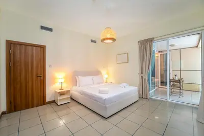 a bedroom with a white bed and a large window at Spacious Upgraded & Elegant - 1BR in Dubai