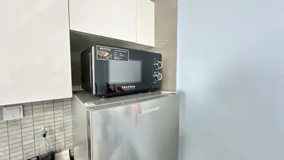 a microwave on top of a refrigerator in a kitchen at Spacious Luxury Studio Near Mall of the Emirates with Pool Access in Dubai