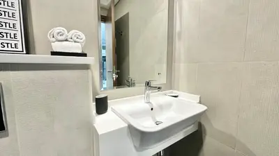 a white bathroom with a sink and a mirror at Spacious Luxury Studio Near Mall of the Emirates with Pool Access in Dubai