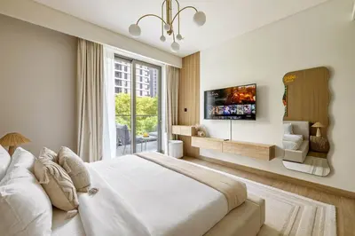 a bedroom with a large bed and a tv on a wall at Spacious 1BR with Pool, Gym & Kids Play Area in Dubai