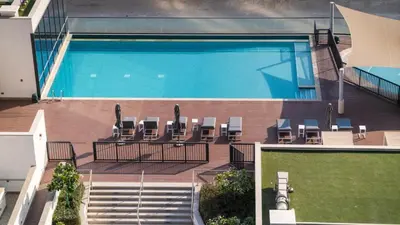 a swimming pool with lounge chairs next to a building at New Cosy 1BR with Pool & Gym in City Centre in Dubai