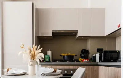 a kitchen with white cabinets and a table with chairs at New Cosy 1BR with Pool & Gym in City Centre in Dubai