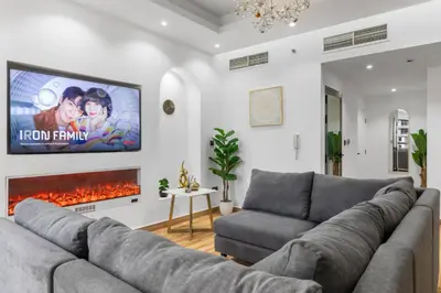 a living room with a couch and a tv on a wall at 2BR Marina View - Beach Access - Sleeps 8 in JBR in Dubai