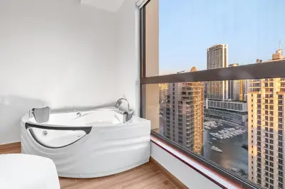 a bathroom with a bath tub in front of a window at 2BR Marina View - Beach Access - Sleeps 8 in JBR in Dubai