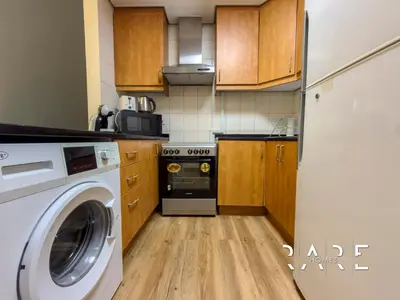 a kitchen with a washing machine and a washer at Rare Holiday Homes - Near Metro - Garden View - Mogul Cluster - Building# 204 - RG09 - Discovery Gardens in Dubai