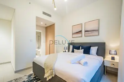 a bedroom with a large white bed with blue pillows at Bright 2BR in Surf at Creek Beach Building 1, Creek Harbour by Deluxe Holiday Homes in Dubai