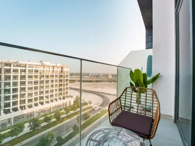 a chair on a balcony with a view of a building at EasyGo - Bright and Airy Studio in Azizi Riviera 9 in Dubai