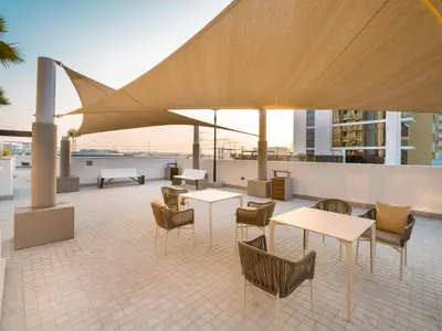a patio with tables and chairs on a building at EasyGo - Bright and Airy Studio in Azizi Riviera 9 in Dubai