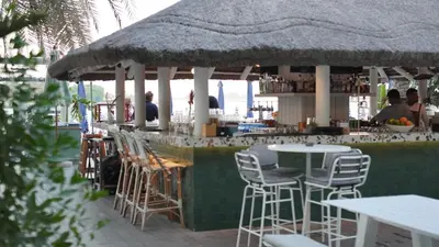 a bar with chairs and tables and a straw umbrella at 2 Bedroom beach front apartment in Dubai