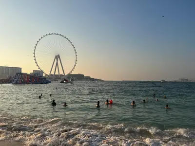 a group of people swimming in the ocean with a ferris wheel at One bedroom apartment available in Front of Marina Beach Dubai in Dubai