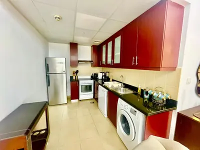 a kitchen with red cabinets and a white refrigerator at One bedroom apartment available in Front of Marina Beach Dubai in Dubai