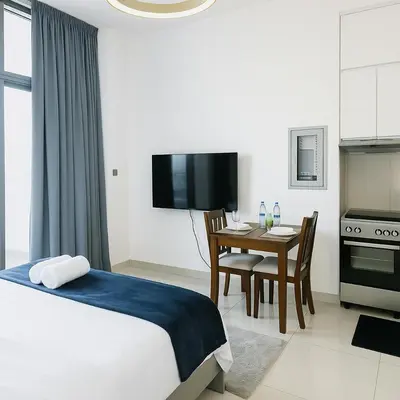 a bedroom with a bed and a table and a kitchen at Dezire Delight in Dubai