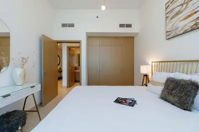 a bedroom with a large white bed and a desk at Cozy and Stunning Waterfront One Bed in Dubai