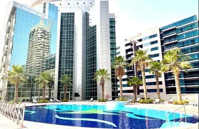 a large swimming pool with palm trees and buildings at Fully upgraded luxurious one bedroom between Marina and JBR in Dubai