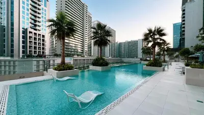 a swimming pool with a chair and palm trees on a building at Outstanding New Studio With 2 Double Beds,In Downtown in Dubai