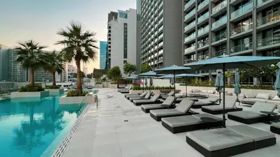 a pool with lounge chairs and umbrellas next to a building at Outstanding New Studio With 2 Double Beds,In Downtown in Dubai