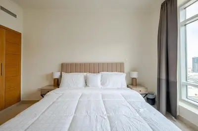 a bedroom with a large white bed with a window at 2BR Luxury Apartment in Downtown Opposite Mall and Fountain Entrance in Dubai