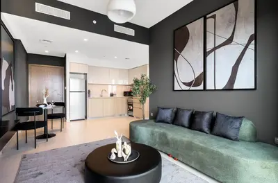 a living room with a green couch and a kitchen at Urban Zen Sky Suite 1BR - Dubai Mall Access by Maxx Value homes in Dubai
